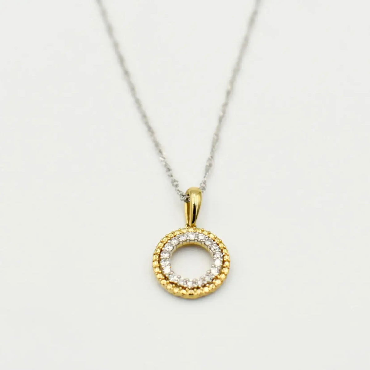 9ct white gold circle pendant necklace with 0.10ct diamonds and yellow gold bail on white background