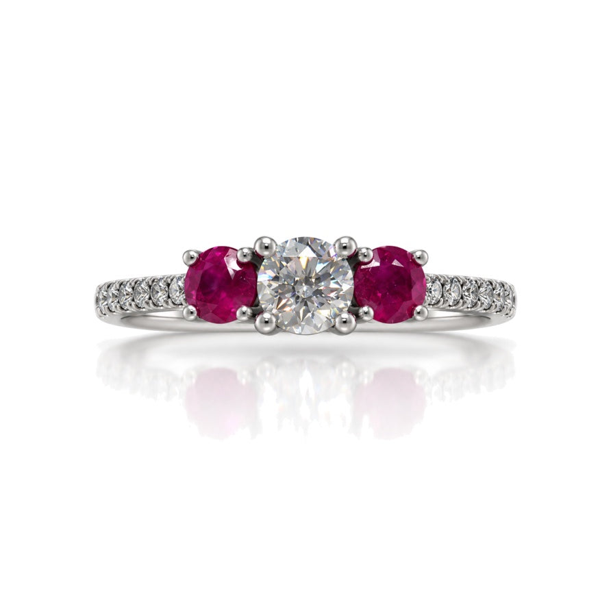 9ct white gold trilogy engagement ring with round diamond centre, ruby side stones and pavé diamond shoulders
