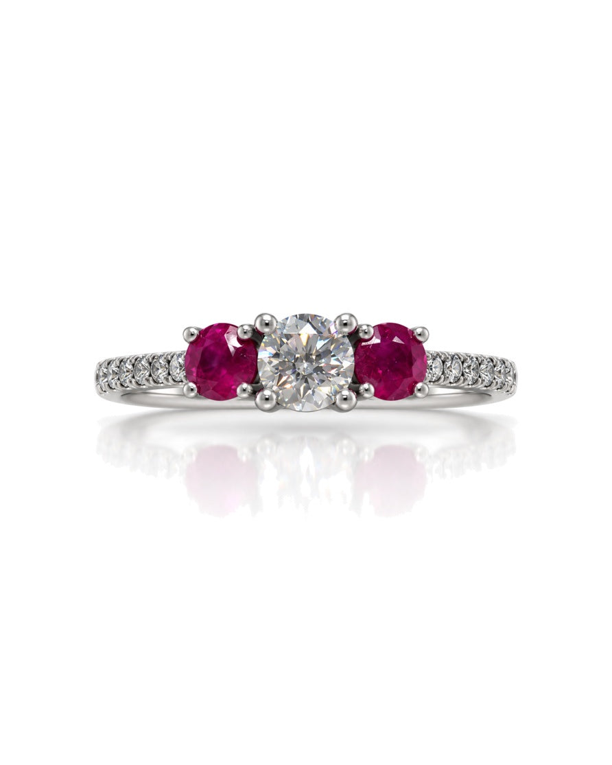 9ct white gold trilogy engagement ring with round diamond centre, ruby side stones and pavé diamond shoulders