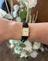 Gold-tone baton hour markers and hands on champagne rectangular dial