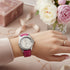 Cassims&Co. Breitling Colt Lady watch with white dial and pink leather strap worn on a wrist with floral background