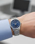 Cassims&Co. Casio quartz watch with a blue sunburst dial and stainless steel bracelet worn on a wrist.