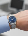 Cassims&Co. Casio quartz watch with a blue sunburst dial and stainless steel bracelet worn on a wrist.