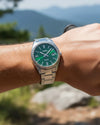 Cassims&Co. Casio Enticer watch with a green sunray dial and stainless steel bracelet worn on a wrist outdoors.