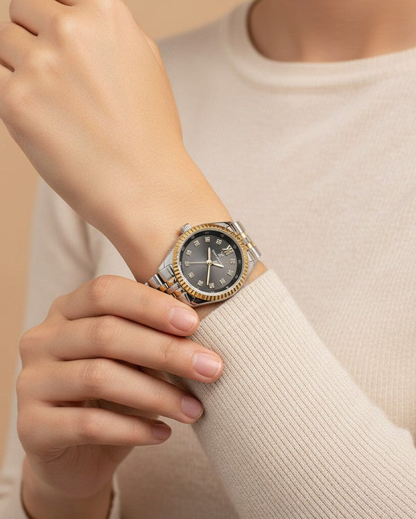 Cassims&Co. Daniel Klein two-tone ladies watch with a black dial, crystal markers, and gold-tone fluted bezel on wrist