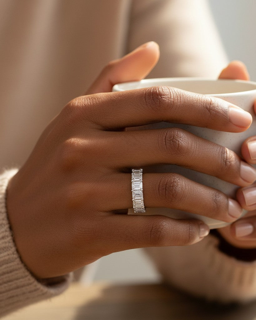 Cassims&Co. 9ct white gold eternity ring featuring nine emerald-cut lab grown diamonds on a woman's finger.
