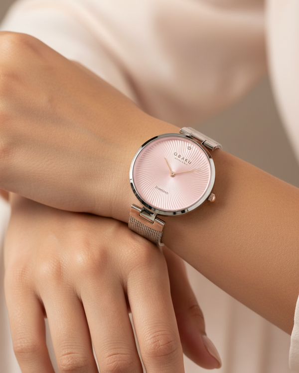 Cassims&Co. Obaku Diamant watch with a pink sunburst dial, diamond accent, and stainless steel mesh strap on a wrist.