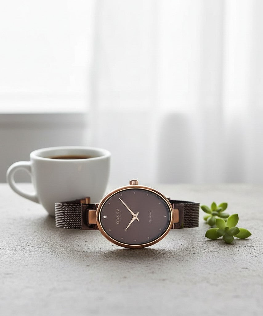 Cassims&Co. Obaku Denmark oval rose gold watch with a brown dial and mesh strap, featuring a single diamond accent.