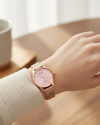Cassims&Co. Obaku Smykke rose gold watch with a pink sunburst dial and diamond accent on a woman's wrist