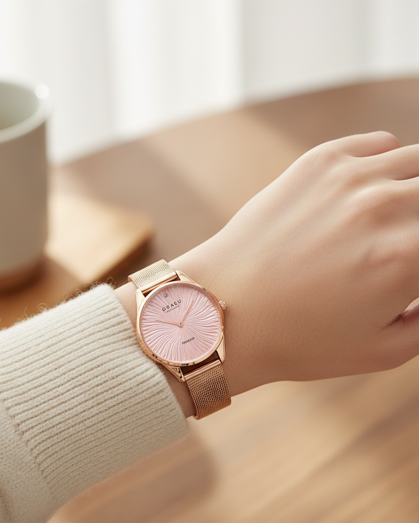 Cassims&Co. Obaku Smykke rose gold watch with a pink sunburst dial and diamond accent on a woman's wrist