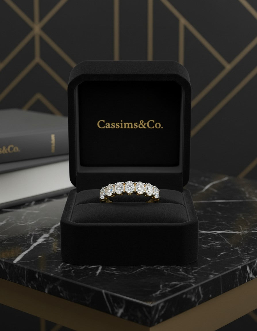 Cassims&Co. 9ct yellow gold seven-stone oval lab grown diamond ring displayed in a black velvet jewellery box.