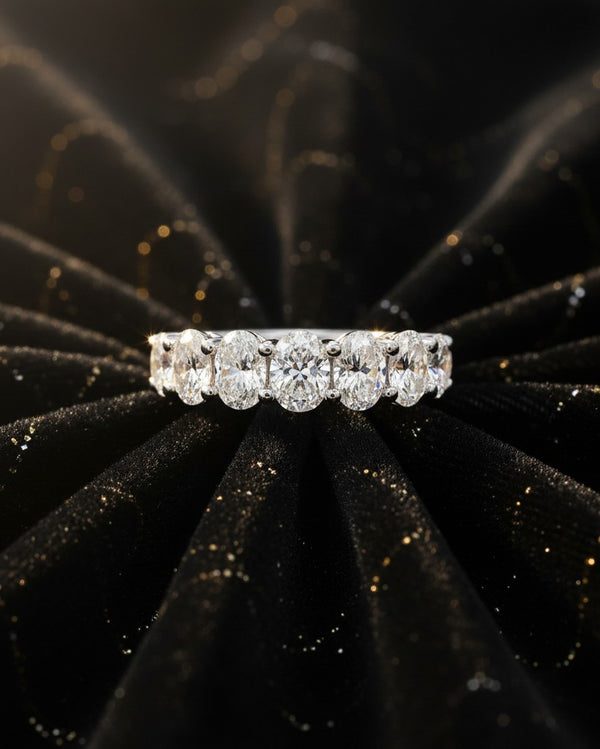 Cassims&Co. 9ct white gold seven-stone oval lab grown diamond ring on a black velvet background.