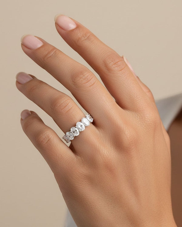 Cassims&Co. 9ct white gold seven-stone oval lab grown diamond ring worn on a woman's finger.