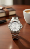 Cassims&Co. pre-owned TAG Heuer Aquaracer watch with white dial, stainless steel case, and bracelet on a desk.