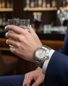 Cassims&Co. TAG Heuer Aquaracer watch with white dial and stainless steel bracelet worn by a man in a suit.