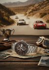 Cassims&Co. TAG Heuer Carrera Calibre 16 watch with brown dial and stainless steel bracelet on a vintage map background.