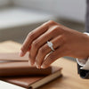 Cassims&Co. 9ct white gold cushion-shaped diamond cluster engagement ring with pavé band worn on a woman's finger.