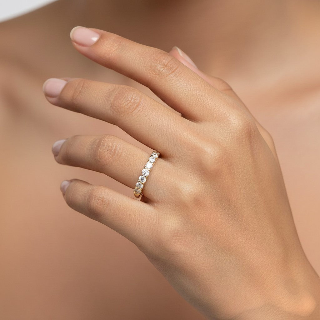 Cassims&Co. 9ct yellow gold eternity ring featuring a row of brilliant lab grown diamonds worn on a woman's finger.