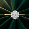 Cassims&Co. 9ct yellow gold diamond flower cluster engagement ring on a dark green velvet background.