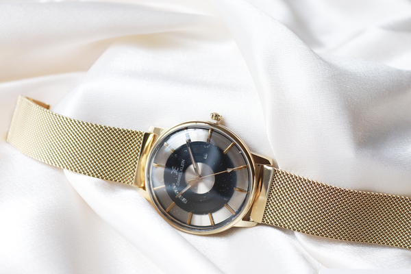Daniel Klein DK112704-5 gold-tone mesh bracelet watch with black and silver gradient dial on white fabric background